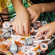 Kids' hands reaching into a bowl of lollipops